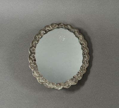 miroir plaqué argent avec un bord festonné sur un fond gris