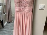 a pink dress hanging on a hanger in front of a window