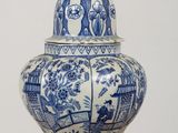 a blue and white vase with a bird on top of it