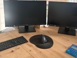 two computer monitors and a keyboard on the table