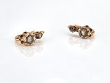 a pair of gold and diamond earrings sitting on top of a white surface