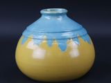 un vase jaune et bleu sur fond noir