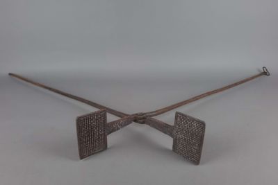 une paire de bâtons en bois croisés, munis de poignées métalliques, sur fond blanc