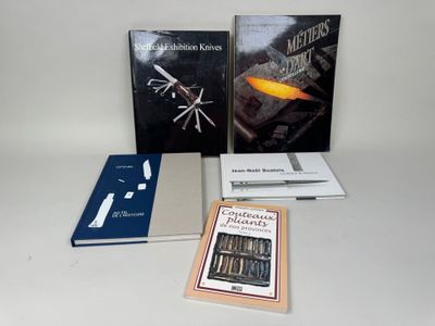 Plusieurs livres sont posés sur une table blanche, devant un fond blanc.