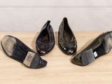 three pairs of black shoes sitting on top of a wooden table