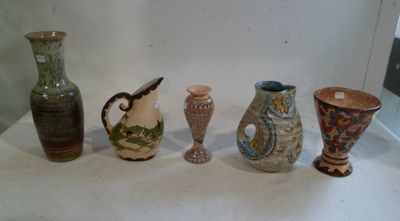 cinq vases différents posés sur une table, sur fond blanc