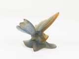 a figurine of a bird that is sitting on a white surface