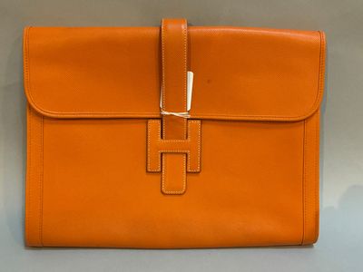 un sac en cuir orange muni d'un fermoir métallique sur le devant