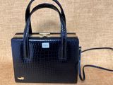 un sac à main en cuir de crocodile noir, muni d'un fermoir doré sur la poignée
