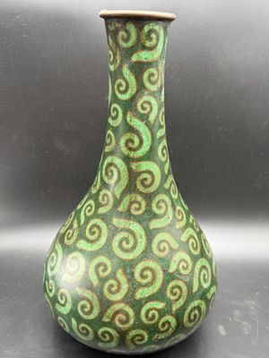 a green and brown vase with swirl designs on it