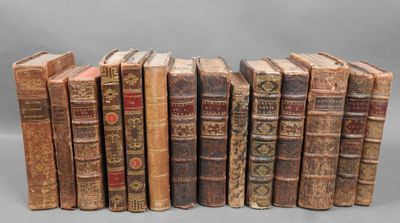several old books are lined up in a row on a gray surface