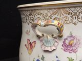 a vase that has a handle on it with flowers on it