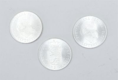 three silver coins are shown on a white surface