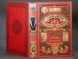 an old book with a red cover sitting on top of a table