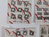 several pieces of paper with red and black designs on them on a white surface