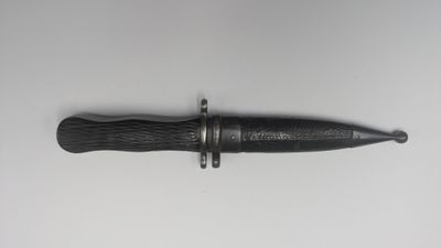 un gros plan d'un couteau au manche noir posé sur une surface blanche