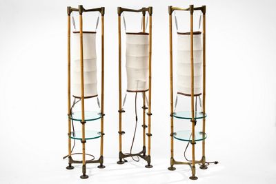 two tall metal and glass floor lamps with glass shelves on each of them
