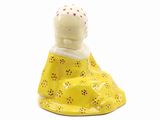 une petite figurine représentant une femme en robe jaune