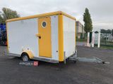 une petite remorque jaune et blanche garée sur un parking