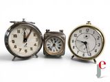 three clocks sitting next to each other on a white surface