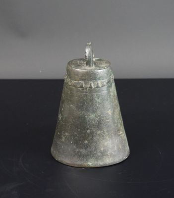 une clochette argentée posée sur une table, sur fond noir