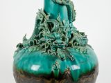 un vase vert orné d'un dragon, posé sur une table