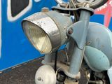 a blue motorcycle parked in front of a wall with graffiti on it