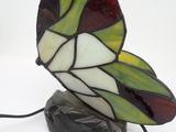 butterfly shaped stained glass lamp sitting on a rock on a white surface