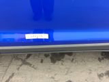 the rear end of a blue car with a sticker on it