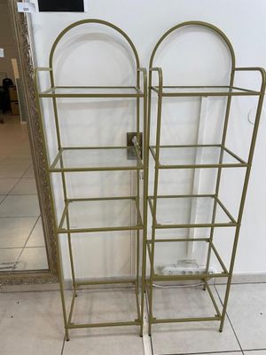 two gold metal shelvings with glass shelves on them