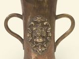 un vase en bronze muni d'une anse, sur fond blanc
