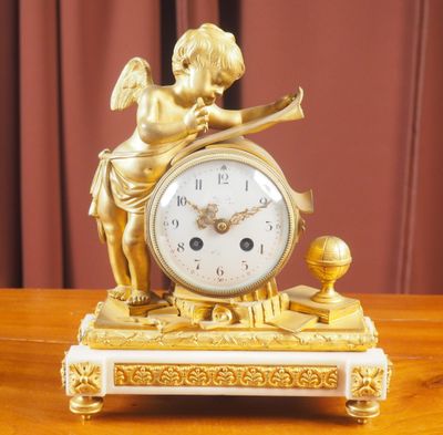 une horloge en or ornée d'un ange, posée sur une table en bois