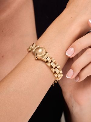woman wearing a gold bracelet and a gold watch on her wrist