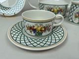 four cups and saucers on a table with a plate