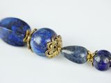 a close up of a necklace with blue beads on a white surface