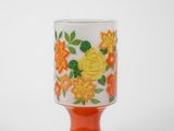 a close up of an orange and white cup with flowers on it