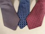 three different colored ties on a table with one red, one blue and one white