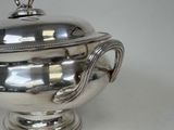a silver bowl with a lid on a white table