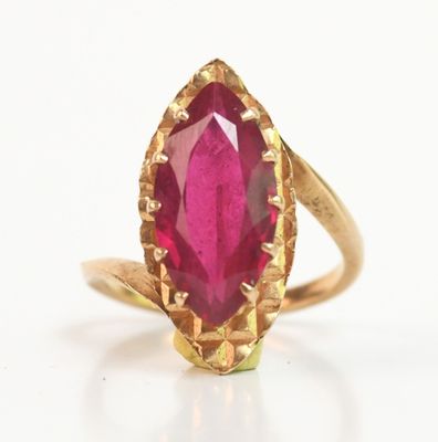 gros plan d'une bague en or avec une pierre rose