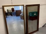 Deux miroirs sont posés par terre devant un mur de briques blanches.