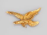 une image représentant une broche en forme d'aigle doré sur un fond blanc