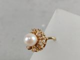 a close up of a gold ring with a pearl and diamonds