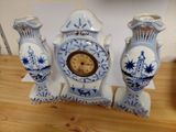three blue and white vases with a clock on them