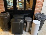 several trash cans are lined up outside of a store front door