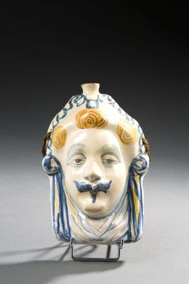 un petit vase orné d'un visage, posé sur un socle