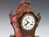 a red clock with a bird on top of it