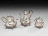 trois théières en argent et une cafetière, posées sur des socles