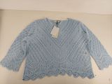 Le pull est bleu et présente un motif en dentelle.