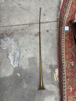 un tapis posé à même le sol, à côté d'une trompette en laiton posée sur un tapis