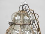 a glass lamp hanging from a chain on a wall